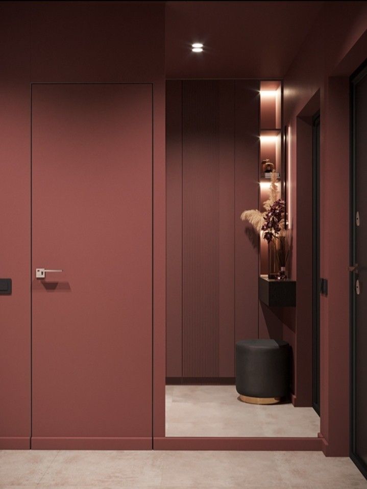 Modern minimalist hallway with pink walls, soft lighting, decorative shelves, and a small round stool.