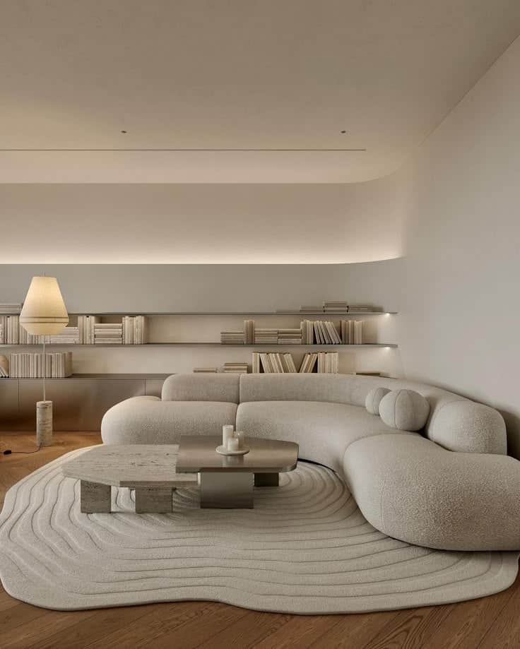 Minimalist living room with a curved sofa, modern coffee table, bookshelves, and soft lighting for a cozy ambiance.