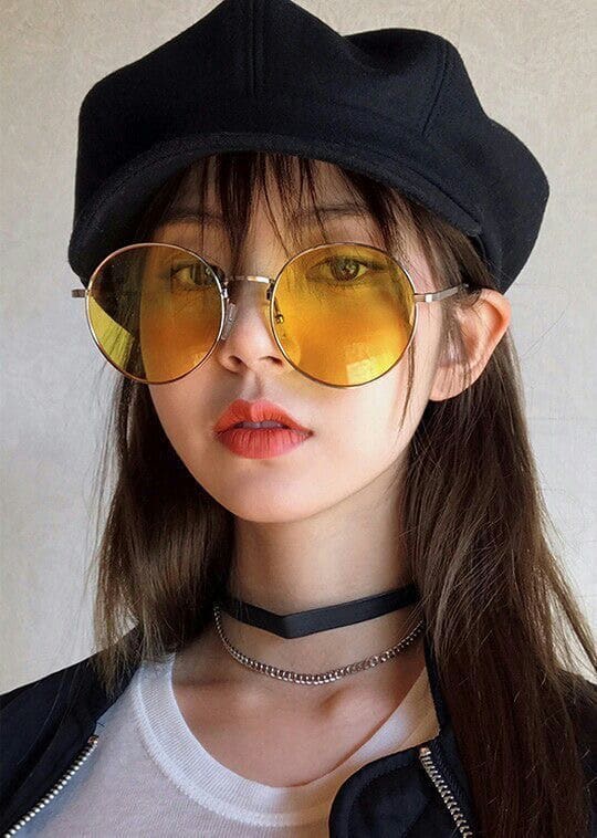 Young woman wearing yellow sunglasses and black hat, stylish and trendy fashion look. Perfect for spring and summer vibes.