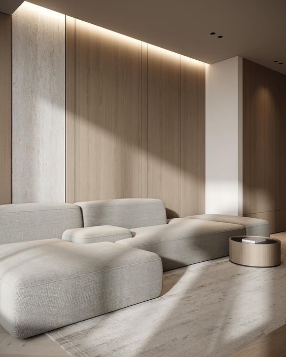 Modern living room with minimalist beige sofa, wooden panel walls, and soft natural lighting.