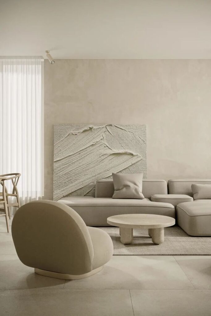 Minimalist living room with beige sofa, abstract wall art, and round coffee table creates a serene ambiance.