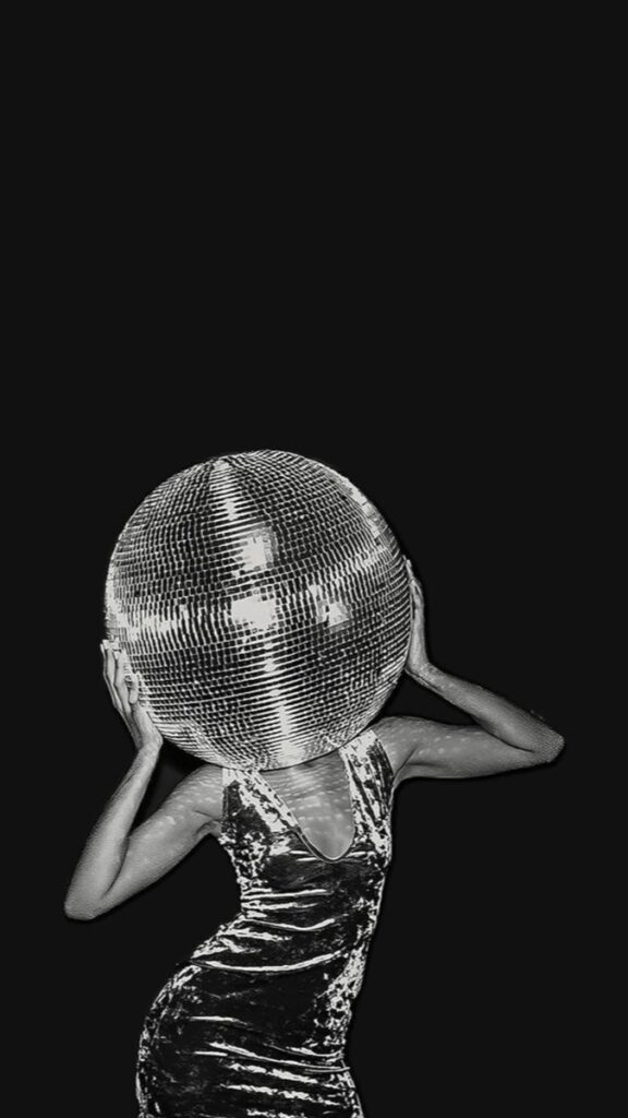 Person wearing a shiny outfit with a disco ball head, striking a pose against a dark background.