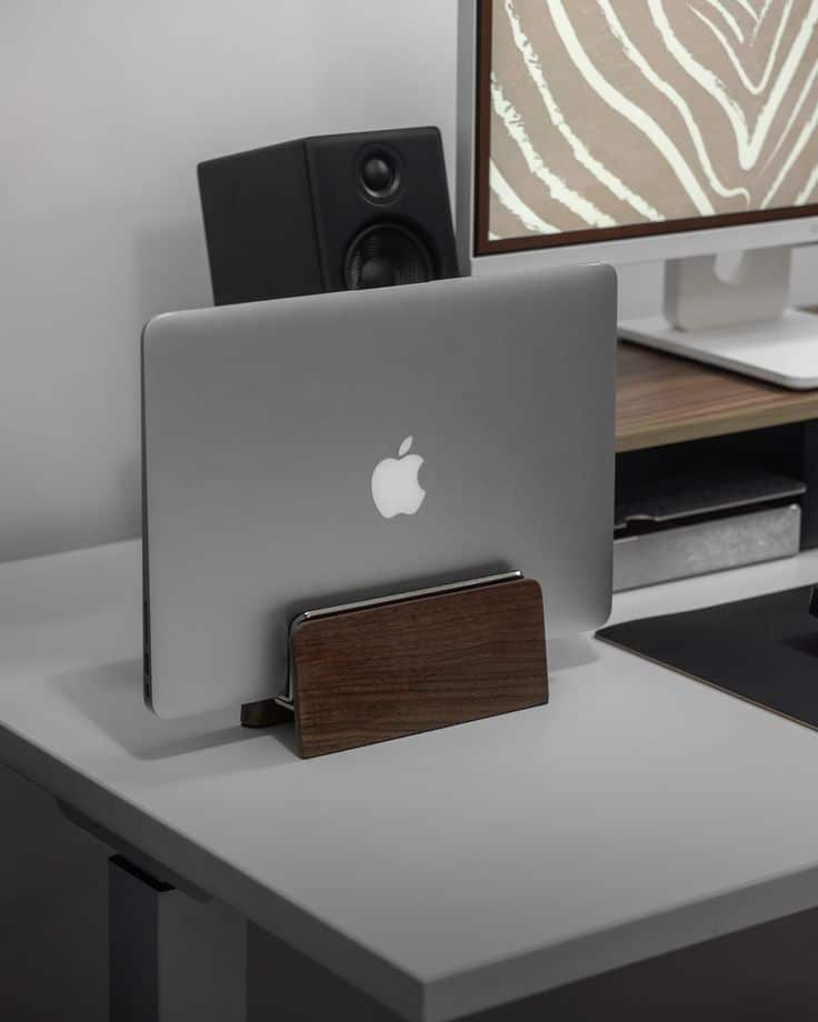 Laptop docked on a minimalist desk setup with monitor and speaker in sleek, modern office design.