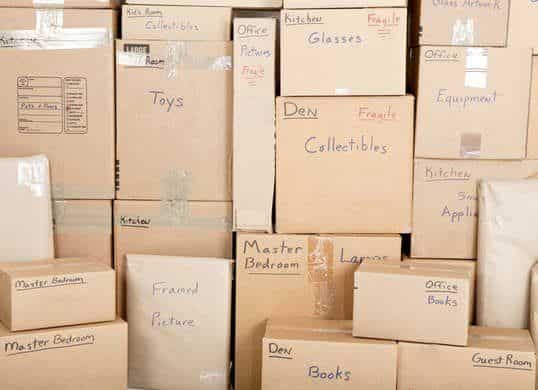 Stacked moving boxes labeled for different rooms and contents, ready for a home move.