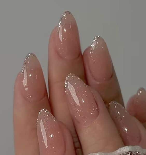 Glossy nude nails with sparkling glitter tips, perfect for elegant and chic manicure inspiration.