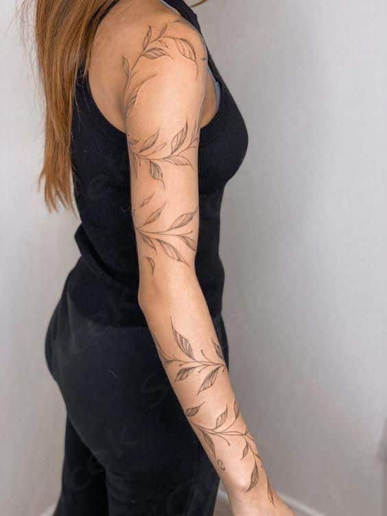 1b2d249d8500d1868c994a0de52824c6 Arm with a leaf-pattern tattoo, wearing a black sleeveless top, showcased against a neutral background. | Sky Rye Design Arm with a leaf-pattern tattoo, wearing a black sleeveless top, showcased against a neutral background.