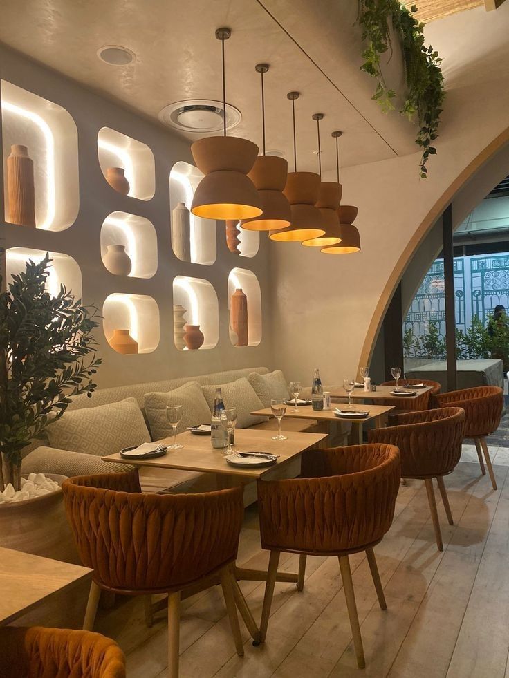 Modern restaurant interior with cozy seating, elegant pendant lights, and decorative wall shelves. Warm ambiance.