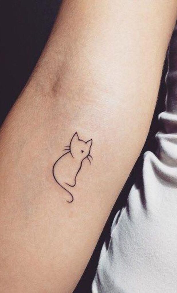 Minimalist cat outline tattoo on forearm, featuring simple lines and a cute feline silhouette.