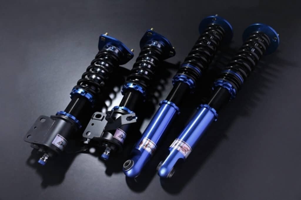 Blue and black car shock absorbers on dark background, showcasing advanced suspension technology.