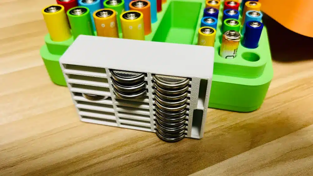 Button cell battery organizer with colorful battery storage tray on wooden table.