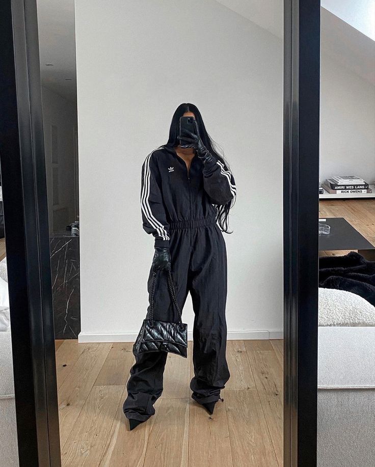 Person in a black Adidas tracksuit holding a quilted handbag, stylish indoor fashion mirror selfie.