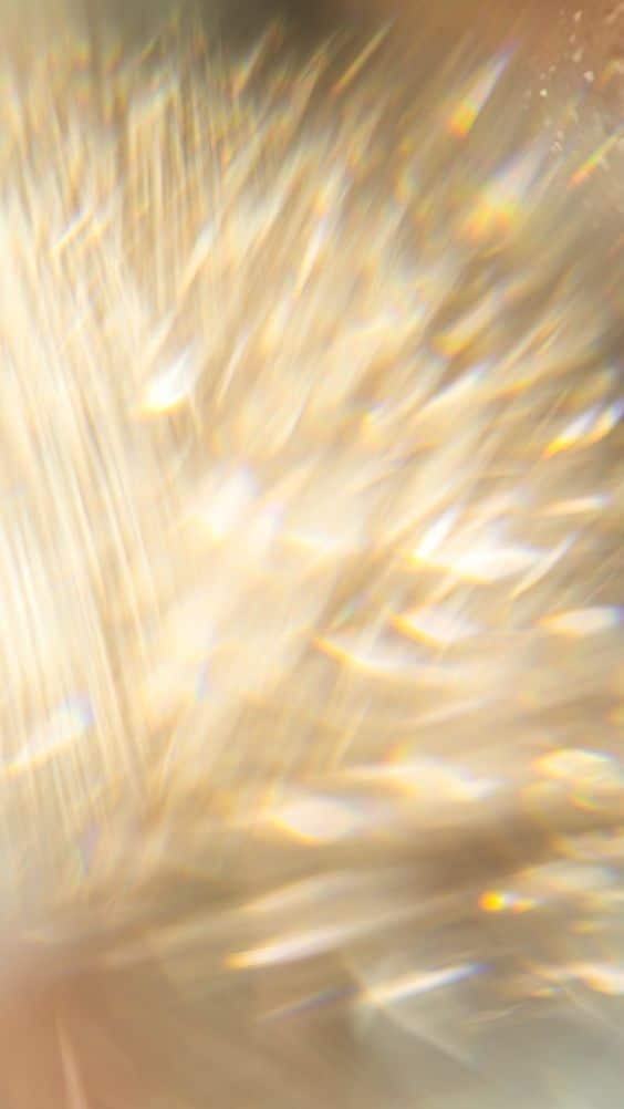 Abstract golden light rays with prism-like rainbow effects, creating a soft, dreamy background with a warm glow.