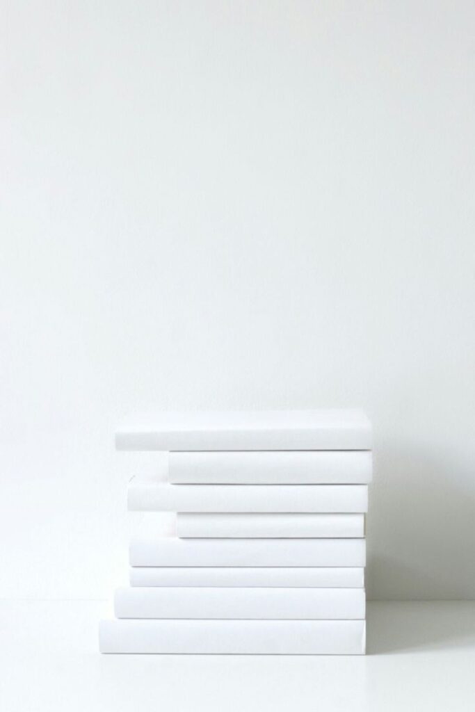 Stack of white books on a minimalist white background, symbolizing simplicity and modern design.