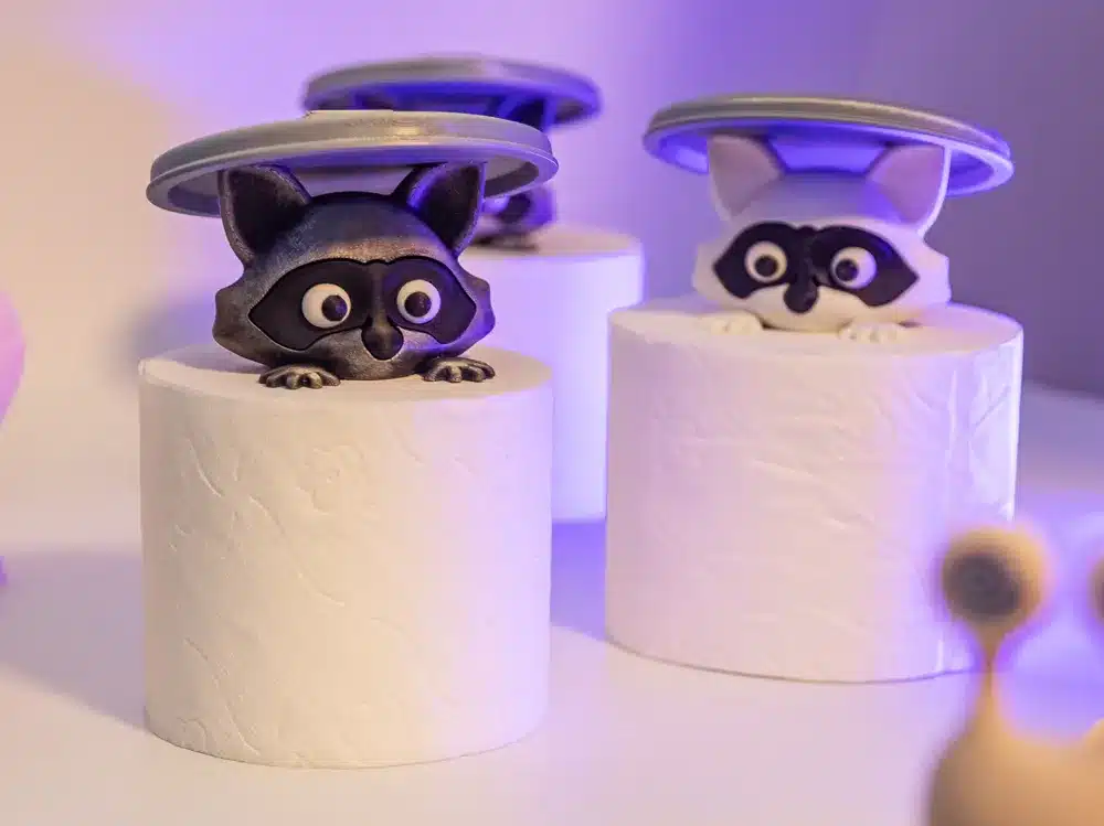 Raccoon figurines emerging from toilet paper rolls, adding a playful touch to bathroom decor.
