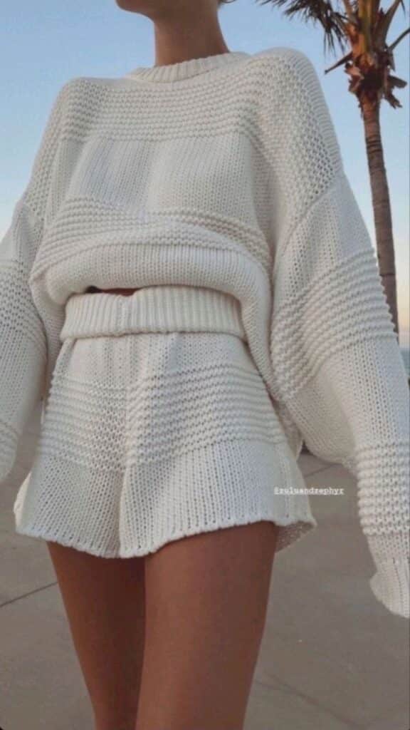 Woman in white knitted sweater and shorts set, outdoor casual look.