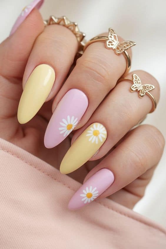 Pastel nails with daisy designs, adorned with butterfly rings. Perfect for a spring-themed manicure.