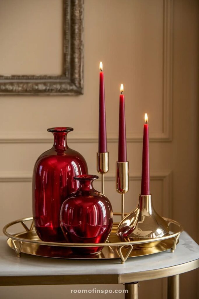 Gold tray with red vases and candles, elegant home decor on a marble table.