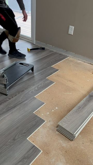 Installing gray laminate flooring with tools in a room. Person working in knee pads.