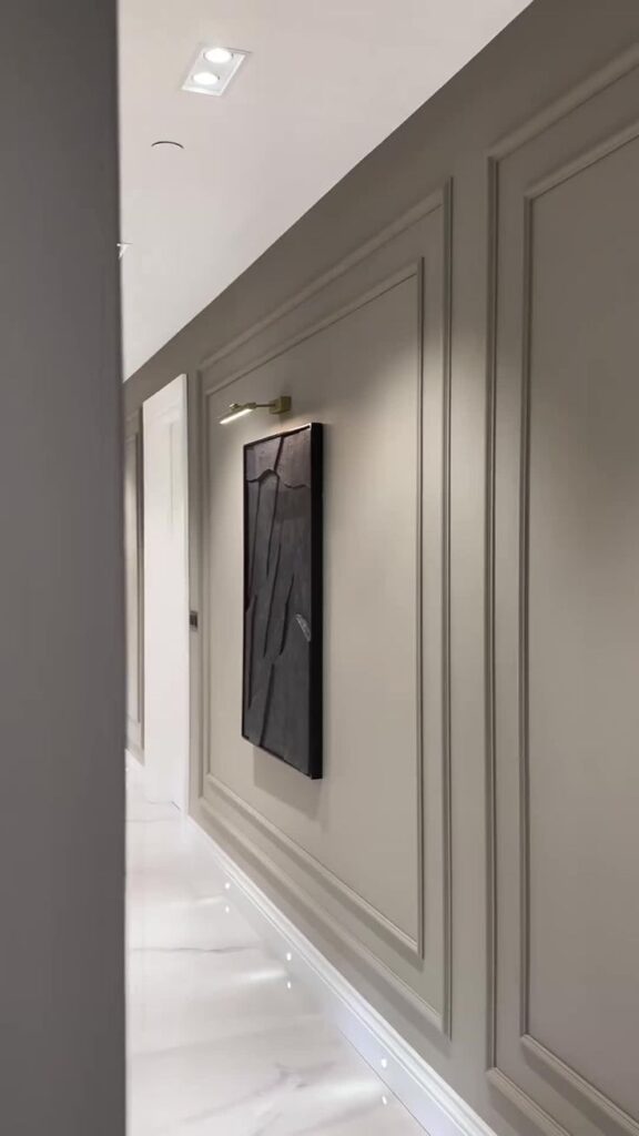 Modern hallway with abstract wall art, recessed lighting, and elegant paneling.