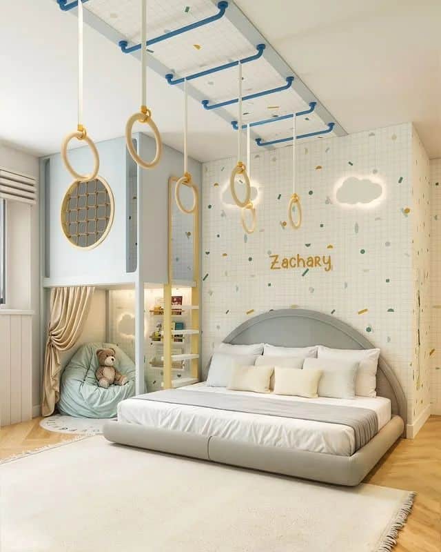 Modern kids' bedroom with climbing rings, cozy bed, and plush decor. Personalized wall with name for a playful touch.