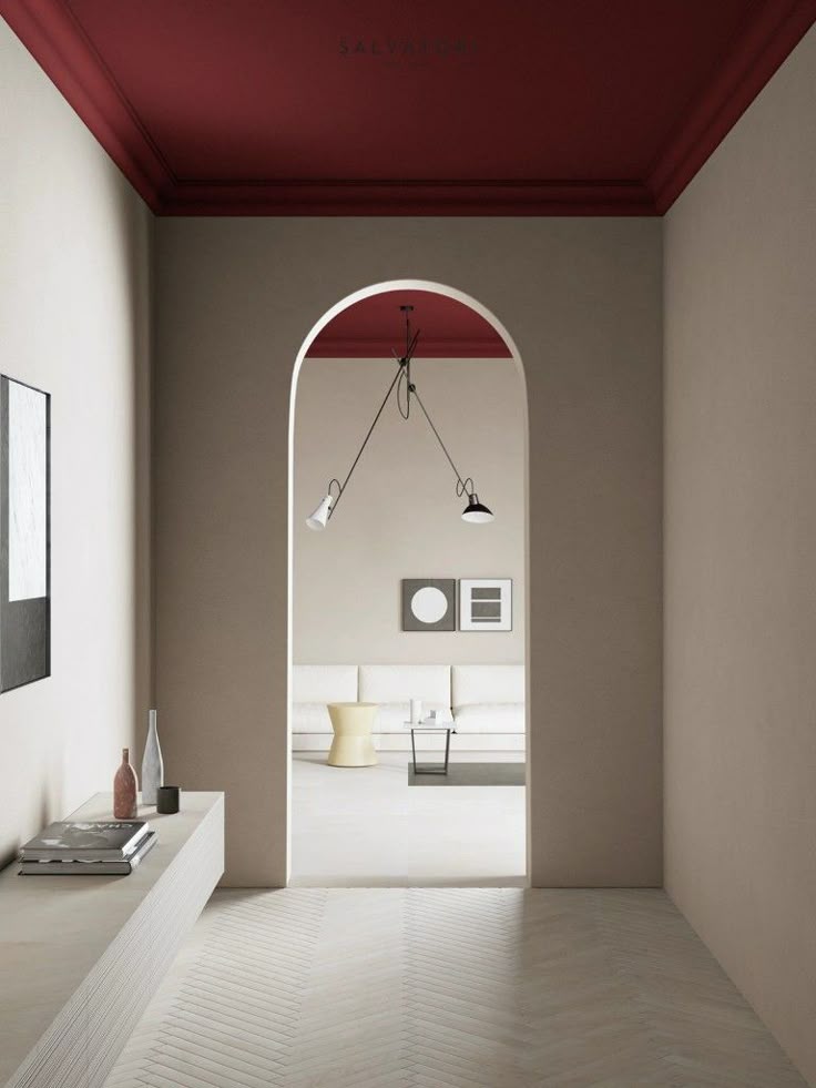 Minimalist interior design with archway, red ceiling, and modern lighting in a neutral-toned room with art and seating.