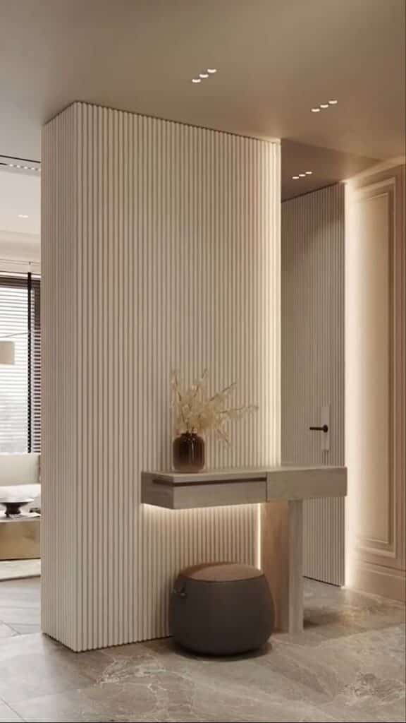 Modern foyer with a minimalist floating console, vase, and ottoman against vertical paneled walls.