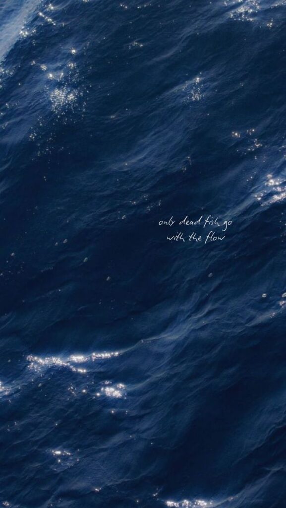 Deep blue ocean waves with sunlight reflections and the text: Only dead fish go with the flow.