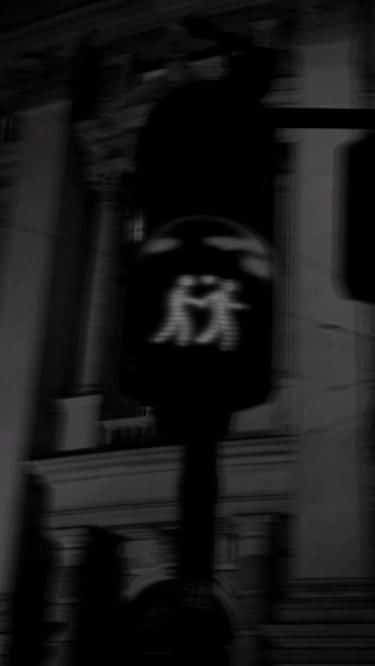 Blurred urban traffic light showing pedestrian symbols with a historic building background at night.