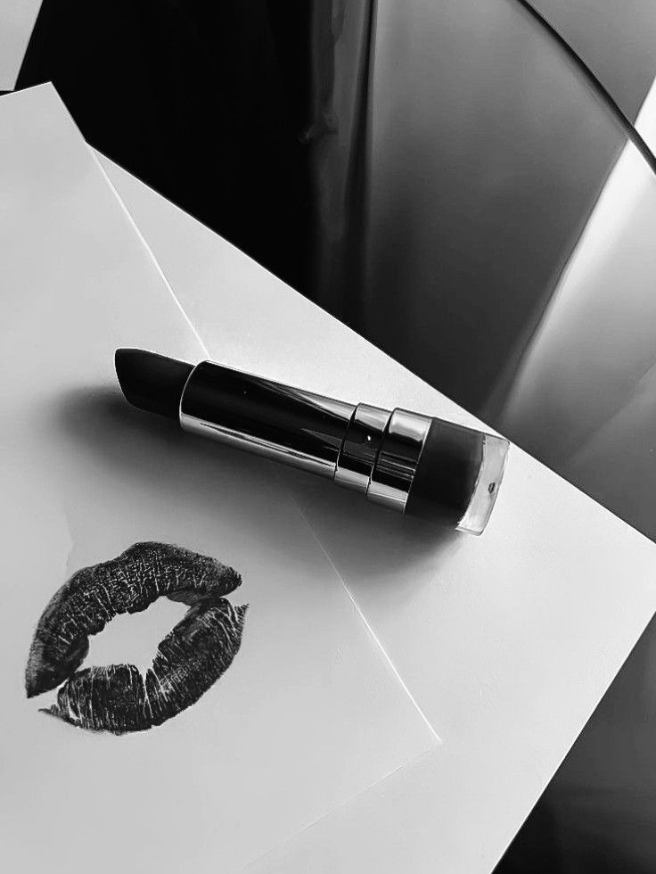 Black and white lipstick on paper with a lip print, reflecting chic elegance and style.