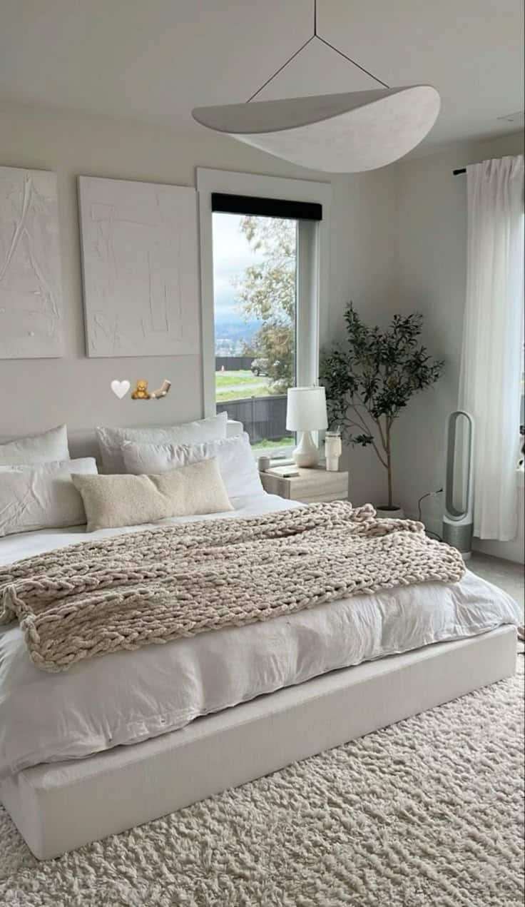 Minimalist bedroom with cozy white bedding, large window, and modern decor. Peaceful and inviting atmosphere.