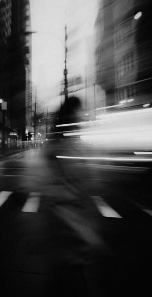 Blurry urban night scene with motion trails and city lights, creating a dynamic and mysterious atmosphere.