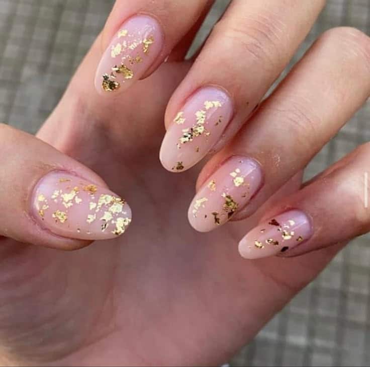 Elegant nude nails with gold foil accents, showcasing a modern and chic manicure style.