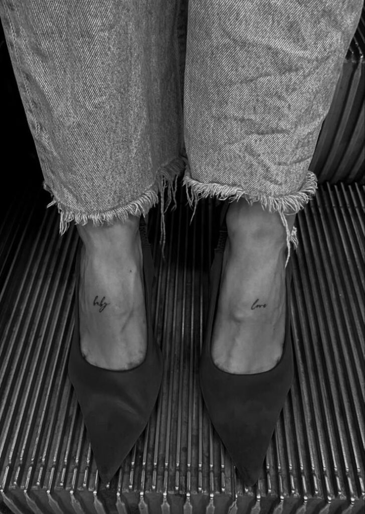 Frayed jeans and pointed shoes on escalator steps, ankle tattoos visible on each foot.