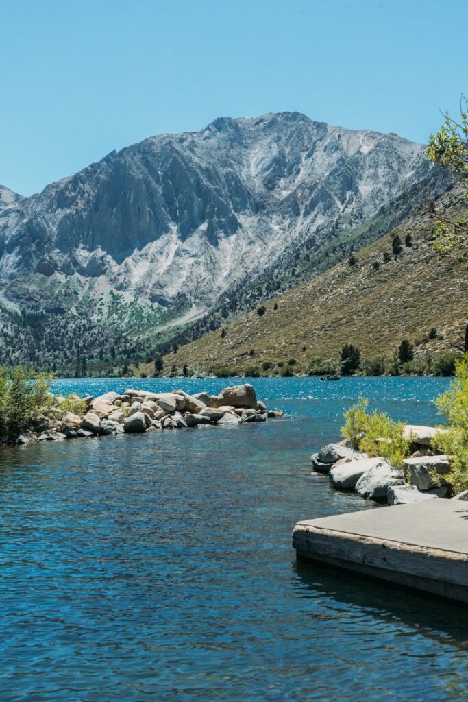 Mountain lake with clear blue water and rocky shore under a clear sky. Perfect for outdoor adventure and nature lovers.