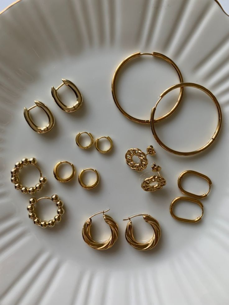 41aeb33e-4d84-4811-9ac6-c6ab26d26fbd A selection of gold hoop and stud earrings on a white dish, showcasing various designs and styles. | Sky Rye Design A selection of gold hoop and stud earrings on a white dish, showcasing various designs and styles.
