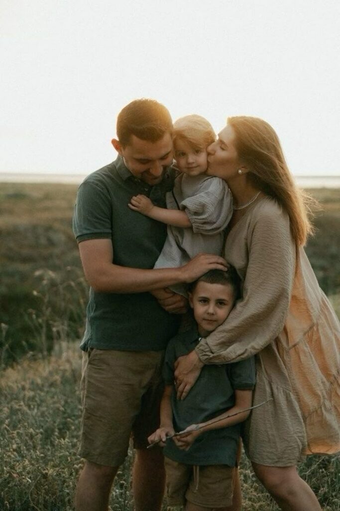 Family enjoying nature together at sunset, parents hugging kids, creating a warm and loving moment outdoors. Photoshoot Ideas