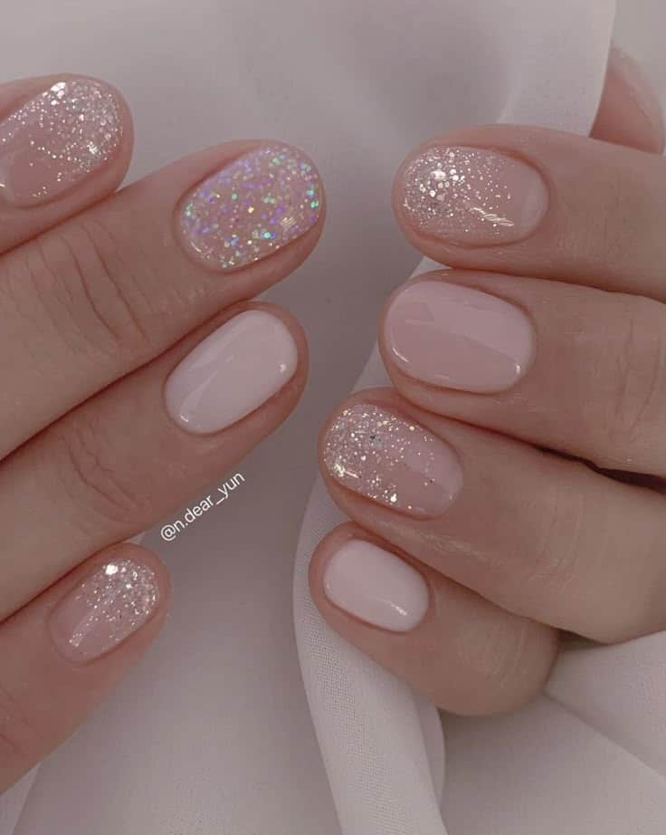 Elegant pink and glitter nail art on short nails, perfect for a chic and subtle manicure look.