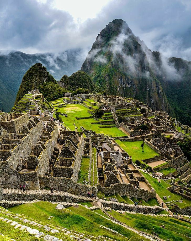 Ancient ruins of Machu Picchu with lush green terraces and misty mountains in the background.
