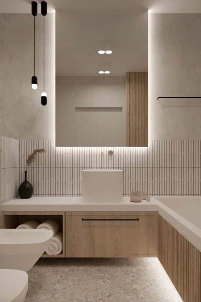 Modern minimalist bathroom with white sink, wooden cabinetry, pendant lighting, and geometric wall tiles.