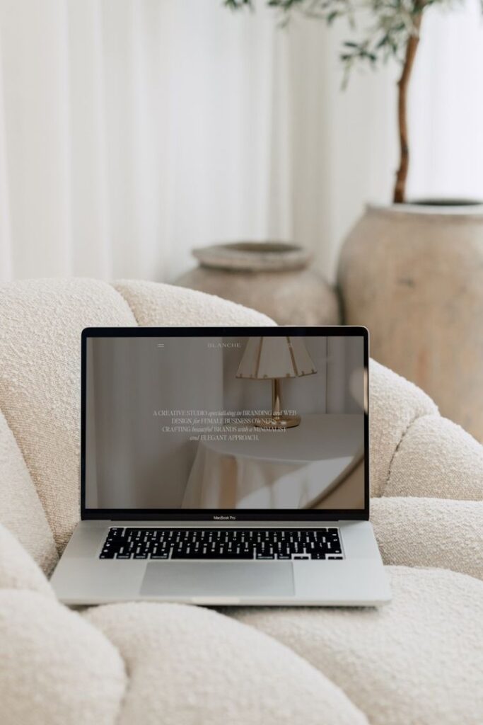 46a7d808-6579-403d-8120-f38e6ad4ec90 Laptop displaying a minimalist website, placed on a cozy beige couch with soft lighting and neutral decor. | Sky Rye Design Laptop displaying a minimalist website, placed on a cozy beige couch with soft lighting and neutral decor.