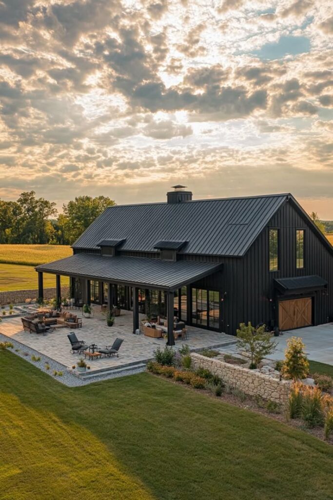 47 Stunning Shouse Barndominiums That Redefine Modern barn-style house at sunset, featuring a spacious outdoor patio and lush green surroundings. | Sky Rye Design Modern barn-style house at sunset, featuring a spacious outdoor patio and lush green surroundings.