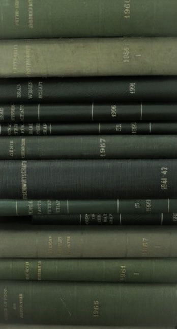 Stack of vintage, green hardcover books with gold text on spines, showcasing varying years and a textured finish.