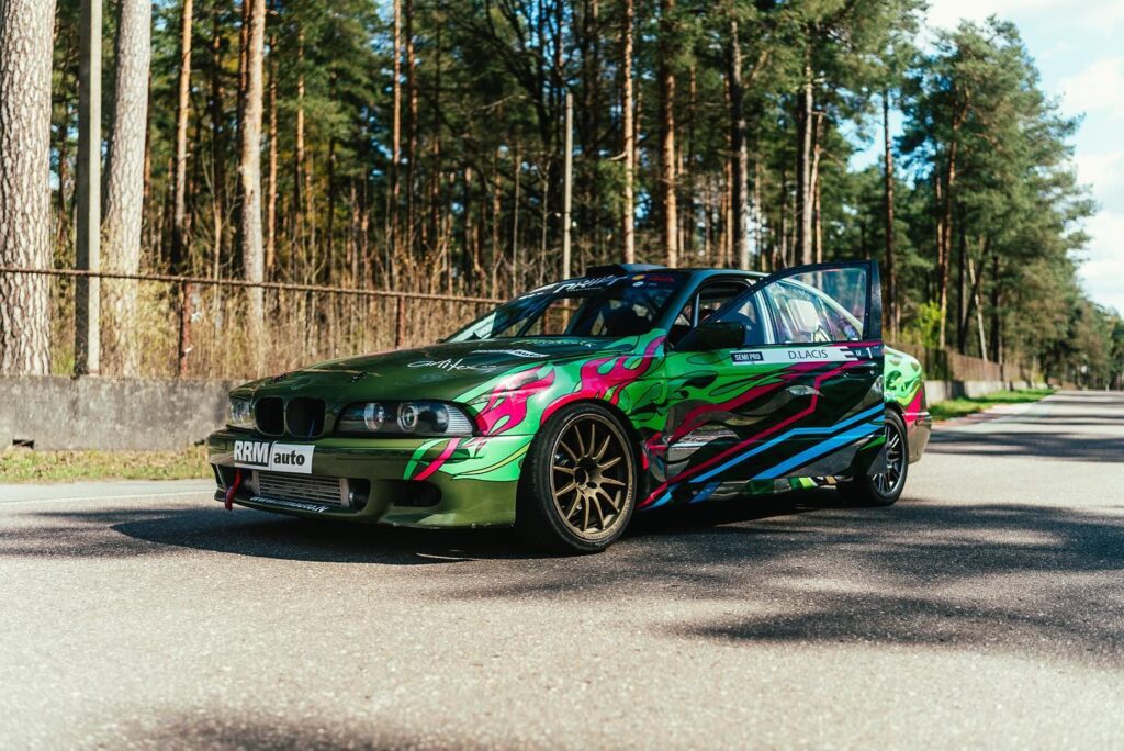 Custom green drift car with vibrant graphics parked on a forest road.