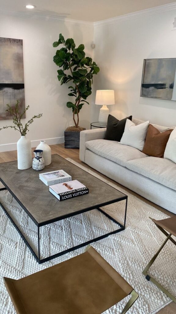 Modern living room with beige sofa, wooden coffee table, art, and indoor plants for a cozy ambiance.