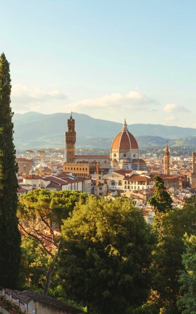 View of Florence skyline with the iconic Duomo and historical buildings against a mountainous backdrop.