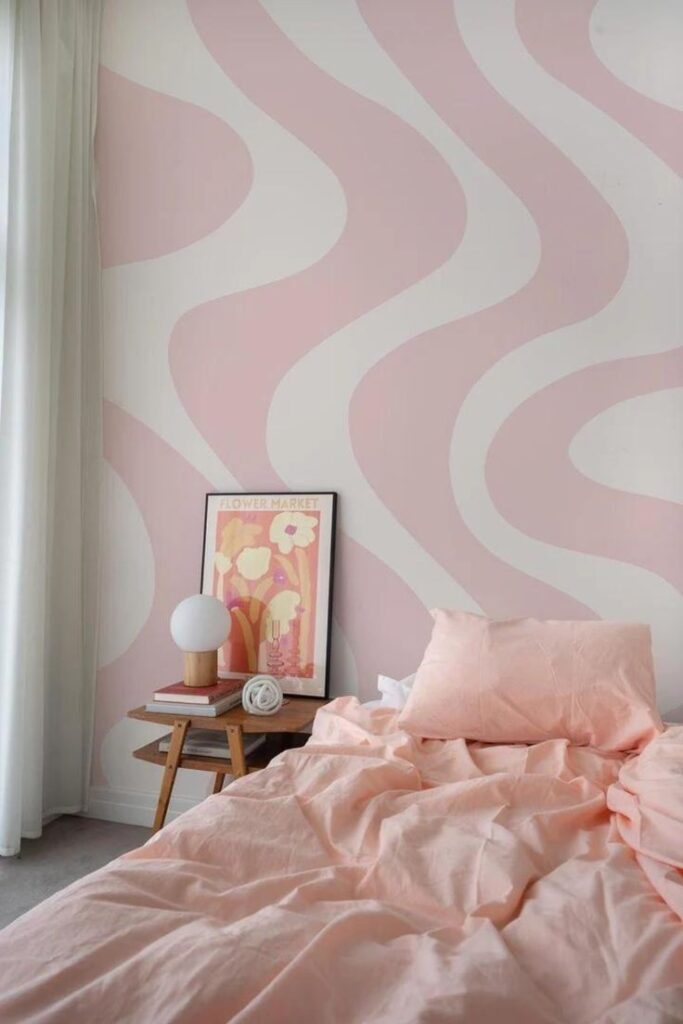 Cozy bedroom with pink wavy wall, matching bedding, side table, lamp, and decorative artwork.