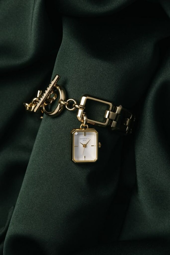4ec45b42-f7d0-4856-98ee-c0422edcf5fe Elegant gold bracelet watch on dark green fabric background. | Sky Rye Design Elegant gold bracelet watch on dark green fabric background.