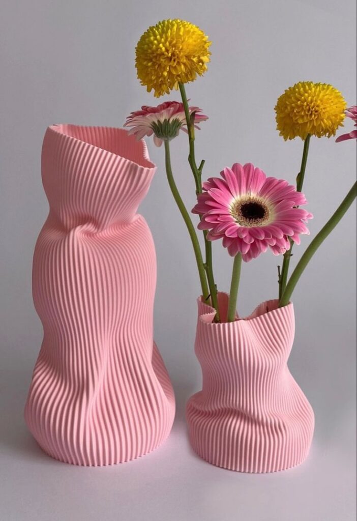 4ece981f-0987-46ad-9588-aac5f96ddf76 Modern pink ribbed vases with yellow and pink flowers against a neutral background. | Sky Rye Design Modern pink ribbed vases with yellow and pink flowers against a neutral background.