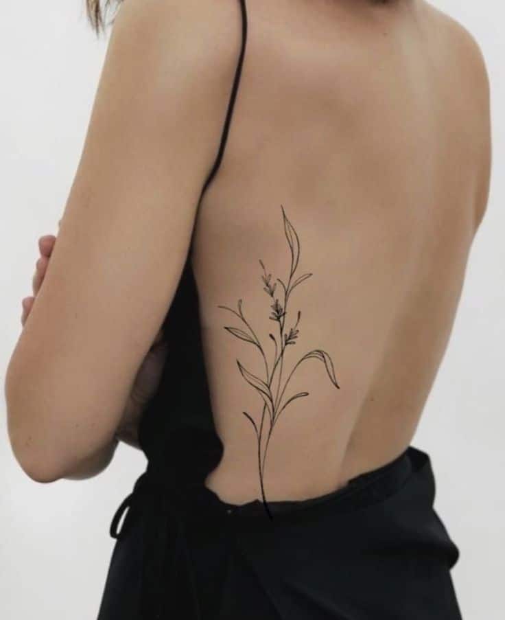 Woman with floral tattoo on back in black dress, showcasing minimalist tattoo design.