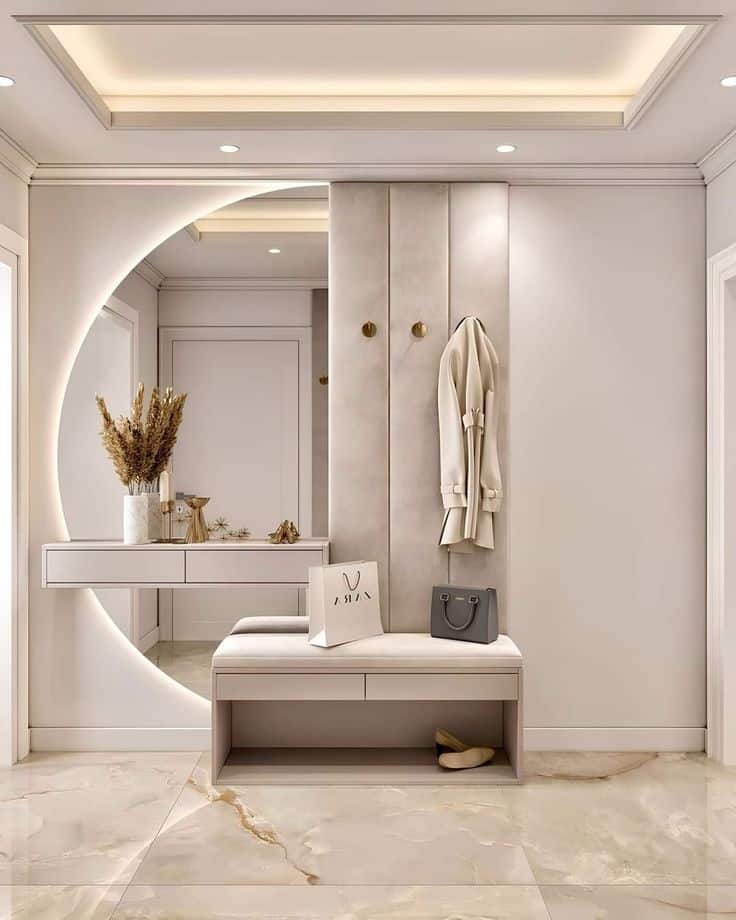 Modern minimalist entryway with stylish bench, coat hooks, round mirror, and elegant decor elements.